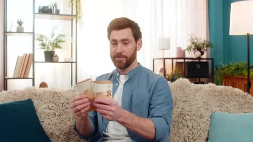 Man Holding Stack of Euro Cash Banknotes Counting Money Smiling Feeling Happy About Big Earnings