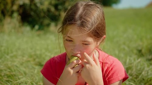 Child Eating Pear Outside on Grassy Field