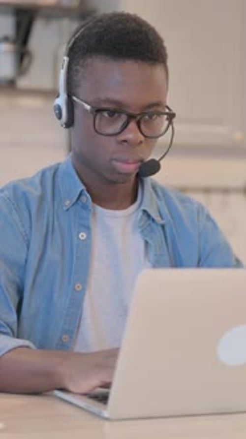 Young Man with Headset Working on Laptop
