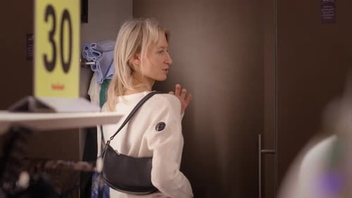 Young girl choosing clothes in fitting room in shopping mall