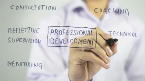 Person Writes Professional Development Topics on Clear Surface