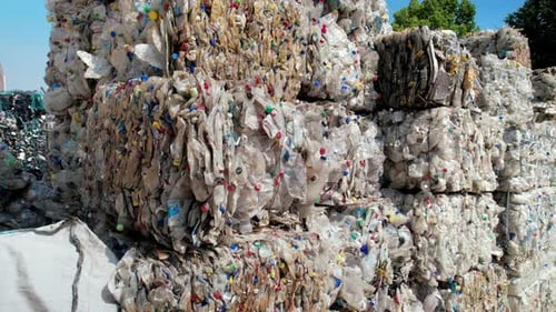 Varios cubos de basura plástica comprimida en una fábrica de reciclaje de residuos al aire libre