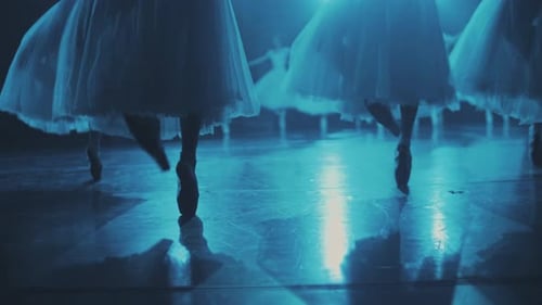 Ballerinas dance on stage in bright blue lighting. Close-up of ballet dancers' feet in pointe shoes