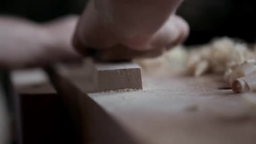 Carpenter sands wood block with sandpaper in his calgary alberta workshop