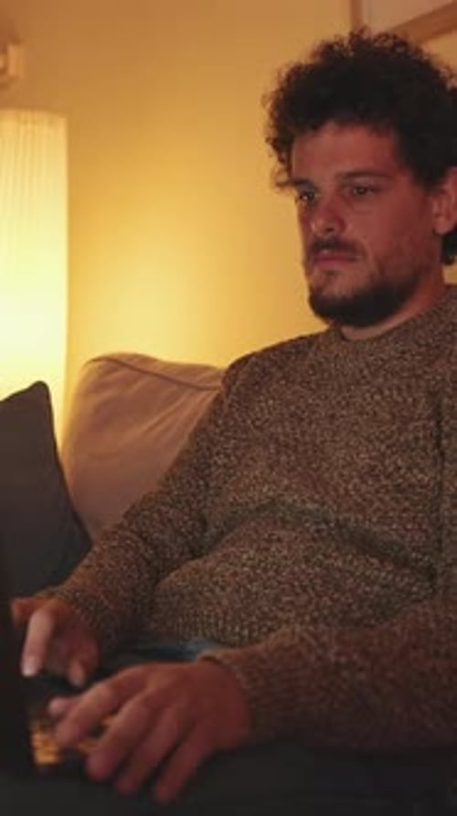 Young Man Uses Laptop on Couch at Night