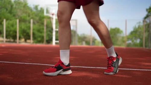 Close Up a Confident Girl Basketball Player in a Summer Sports Uniform and Sneakers Dribbles the