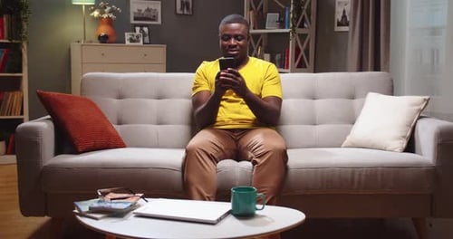 Man Relaxing on Sofa Using Smartphone