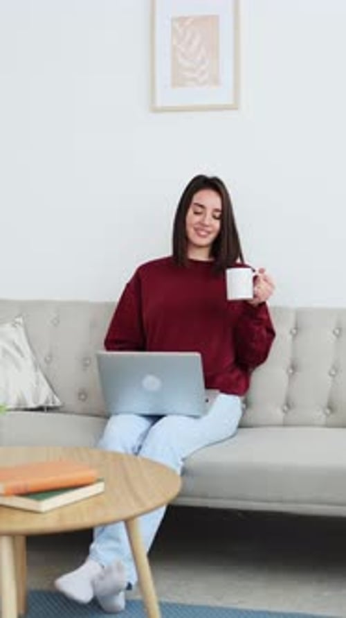 Woman with Laptop and Coffee Relaxing on Couch