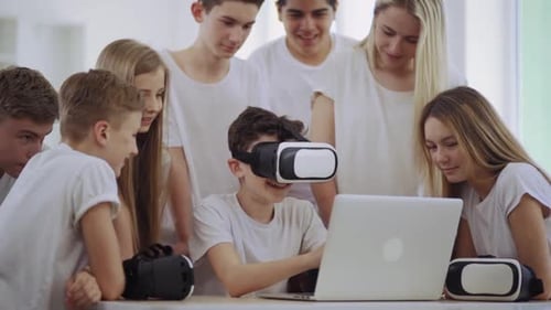 Teens Experience Virtual Reality With VR Headset And Laptop