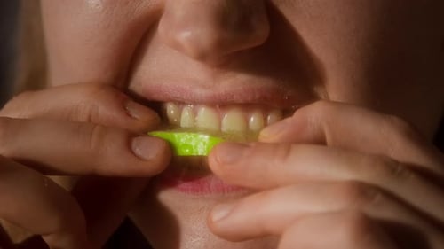 Young Woman Biting Lime Citrus with White Teeth