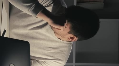 Man Rubs Eyes and Neck While Using Computer