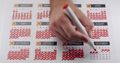 a Person is Writing on a Calendar with a Red Marker