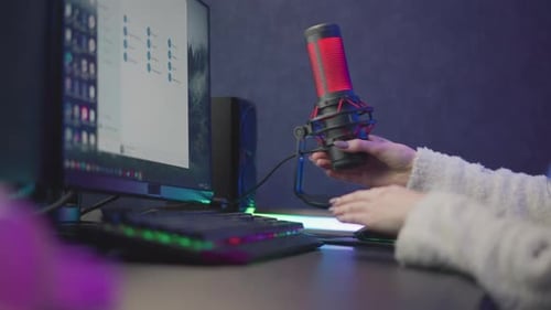 Lady Repositioning Red Studio Microphone and Cable in Cozy RGB Workspace
