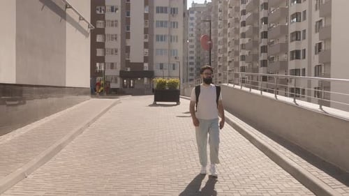 Man Walking on Brick Sidewalk in Urban Setting