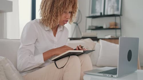 Woman Working on Laptop and Taking Notes