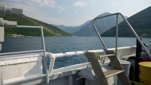 View from the old ferry boat on calm sea waves and high mountains in Kotor bay, Montenegro.