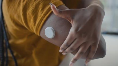 Woman Applying Continuous Glucose Monitor to Arm