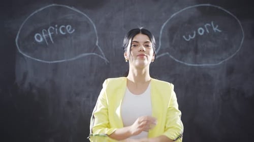 Woman writing Office Worker on blackboard looks at camera with her arms folded.