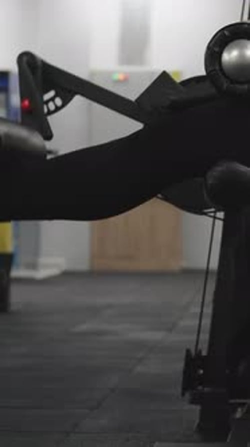 Vídeo vertical. Jovem mulher fazendo exercícios de extensão de pernas em uma máquina sentada
.