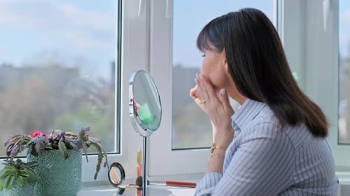 Happy Middle Aged Woman Touching Her Face Admiring Herself in Mirror