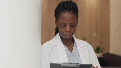 Portrait of Black Female Medical Specialist Holding Clipboard in Clinic Hallway