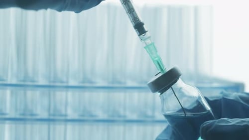 A Doctor is Drawing Up Vaccine From Phial Bottle and Filling Syringe Injection for Vaccination