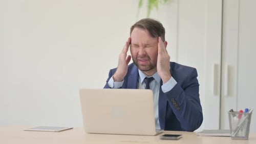 Stressed Businessman Massaging Temples in Office