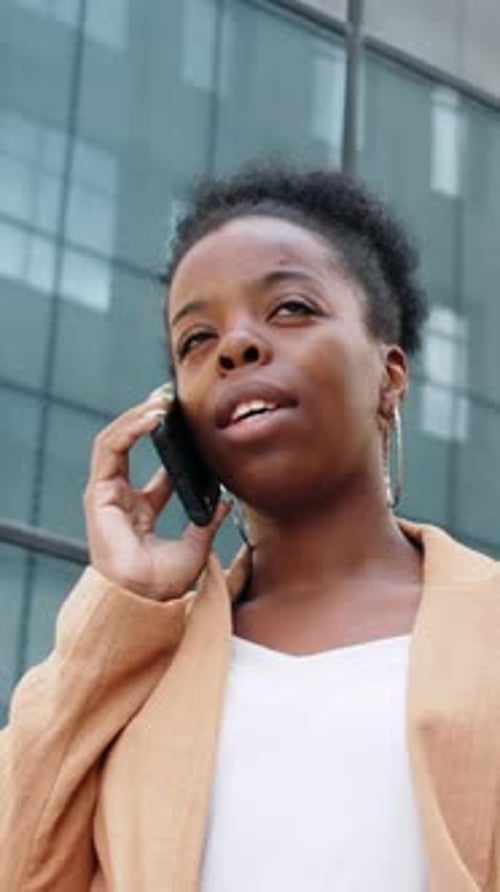 Confident Businesswoman Talking Near Glass Building