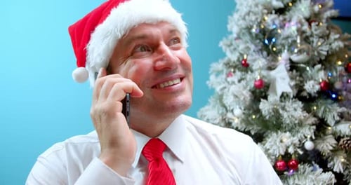 Man in Santa Hat Talking on Phone at Christmas