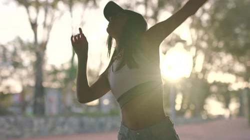 Woman Dancing Outdoors at Sunset in Urban Park