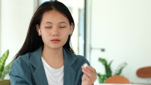 Young Woman Inserts Wireless Earbud
