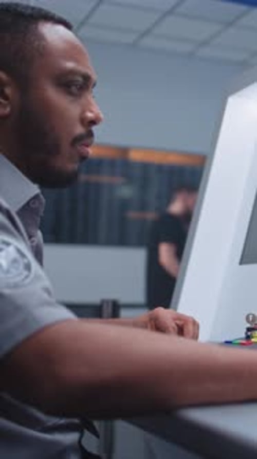 Airport Security Checkpoint Security Officer Monitors Baggage Screening on Computer Screens