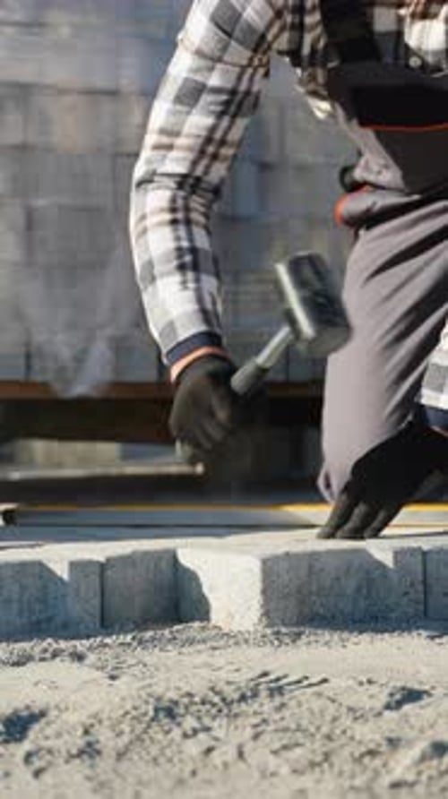 Worker Uses Mallet and Level to Install Pavers
