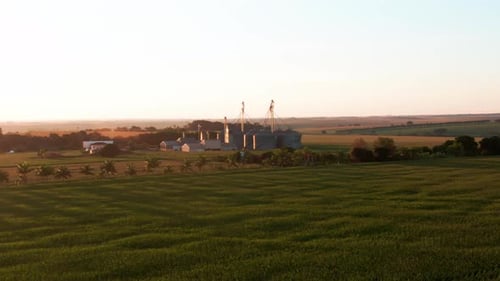 Drone aerial landscape afternoon sunset across countryside crops plantations valley with grain silo