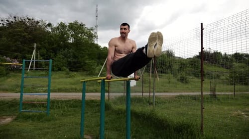 Muscular Man Exercising on Parallel Bars Outdoors