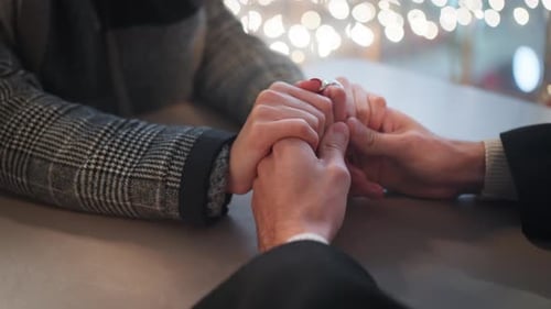 Closeup of Romantic Couple Holding Hands at Cafe Table