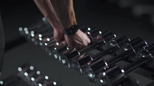 Anonymous Athlete Takes Dumbbells From the Rack Stand in the Gym and Leaves Man Taking Weight