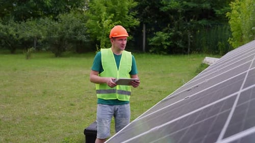 An Engineer Checks Solar Energy Production Indicators Near the Panels