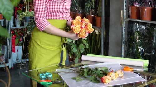 Woman Arranging Orange Roses into Bouquet in Shop
