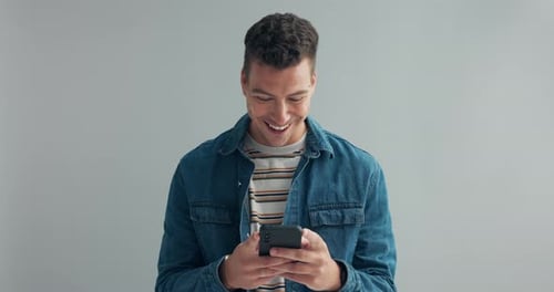 Man, happy or message on cellphone in studio, or notification on mobile app by gray background