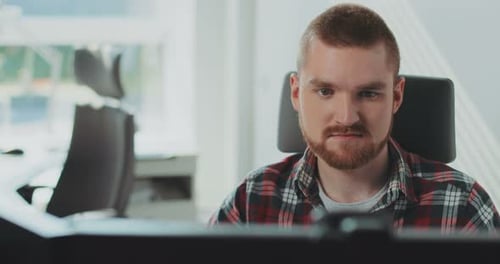 A Young Bearded Man Sits at a Computer Works in the Office Contemporary Design Manager Marketing