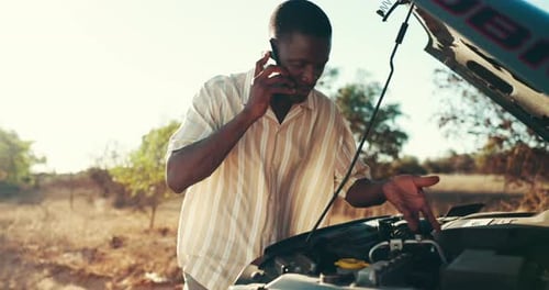 Man Talks on Phone Beside Car With Hood Open