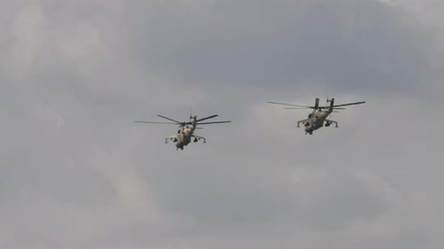 Two Camouflaged Military Helicopters Fly in Formation