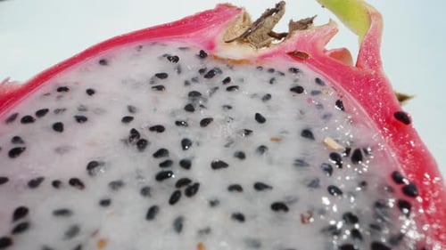 Halves of pitahaya with white flesh, dragon fruit, black seeds. Dolly slider extreme close-up. Laowa