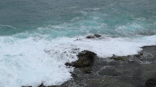 Waves crashing into a rocky formation near the shoreline of a large wave breaking on stones to the s