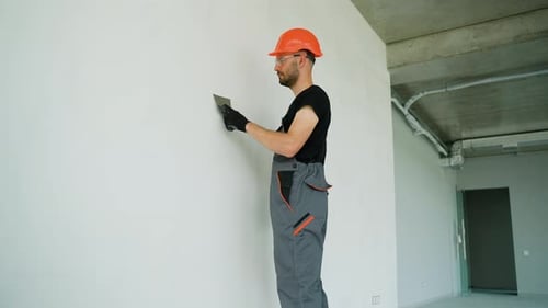 Builder Worker Plastering at Wall in Office