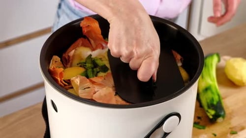 Mujer reciclando residuos orgánicos compostando cáscaras de verduras en el Bokashi en la cocina