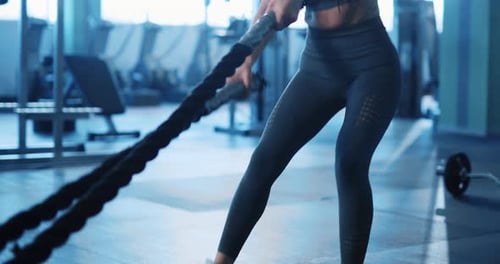 Woman Working Out with Battle Ropes at Gym