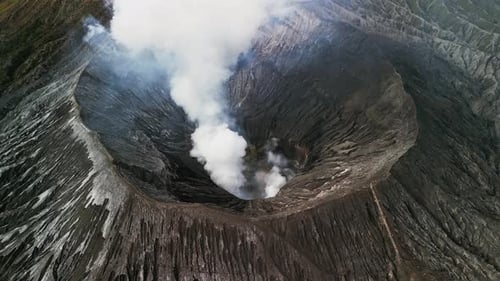 Aerial Drone Footage of Mount Bromo Smoking Crater Rim and Vast Volcanic Terrain Indonesia