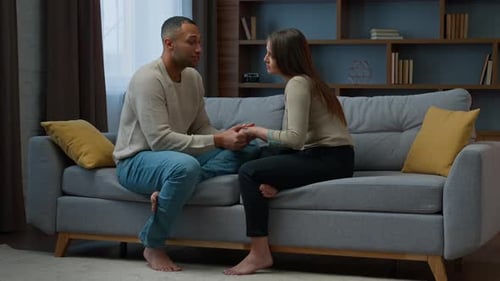 Couple Talking and Holding Hands on Couch